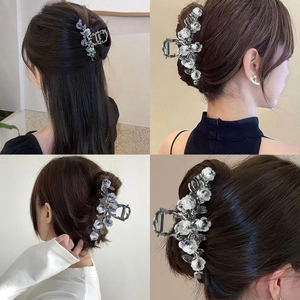 Détail d'une grande pince à cheveux en métal argenté avec fleur de camélia bleue sur coiffures