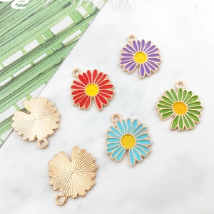 Detail view of colorful daisy flower enamel alloy pendants with golden bases on marble surface