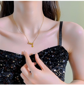 Detail of gold LOVE necklace with heart pendant shown on model neck with sequin dress