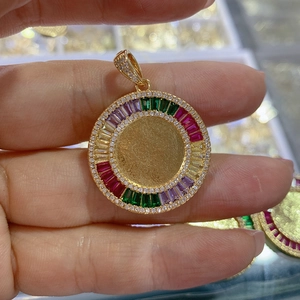 Detail of a gold circular Virgin Mary pendant with multi-color gems and crystal inlay