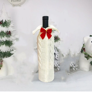 Knitted Christmas wine bottle cover in ivory white with a red bow festive decoration