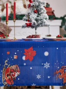 Detailed view of blue Christmas tablecloth featuring Santa, reindeer and snowflake patterns
