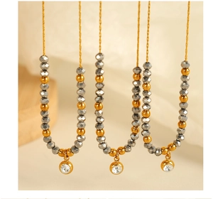 Detail of beaded necklace with grey faceted crystals and gold pendant in warm light