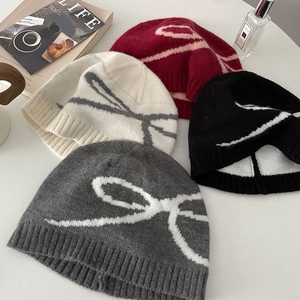 Flat lay of knit beanies in gray black white and red featuring bow patterns
