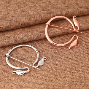 Detailed close-up of vintage Viking metal brooches in rose gold and silver finishes