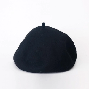 Detail of wool texture and classic top stem on a minimalist black beret hat