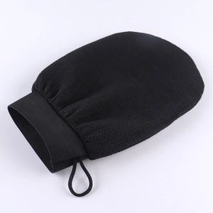 Close-up of black exfoliating glove showing grainy texture, elastic cuff, and hanging loop