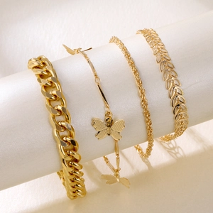 Dettaglio del set di quattro bracciali dorati con farfalle e catene a maglia cubana e foglie
