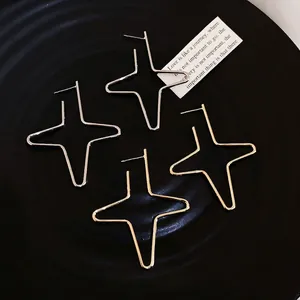 Minimalist geometric star stud earrings in gold and silver finish on a textured black tray