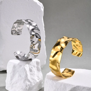 Detailed view of gold and silver stainless steel bangles with irregular wave texture