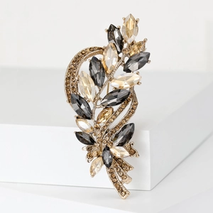 Macro shot of elegant crystal wheat brooch with champagne and grey stones on a white stand