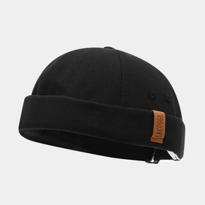 Close-up of black canvas docker hat texture with brown leather brand label detail