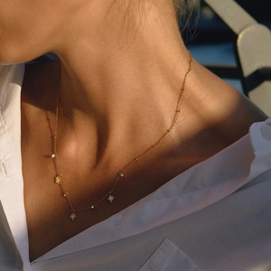 Close-up of a gold titanium steel necklace with star pendants on a model's neck