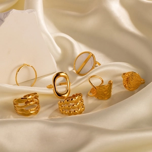 Set of gold titanium steel irregular rings displayed on an elegant silk background