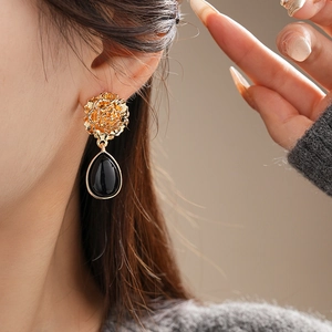 Close-up of vintage flower earrings with black waterdrop pendants on a model