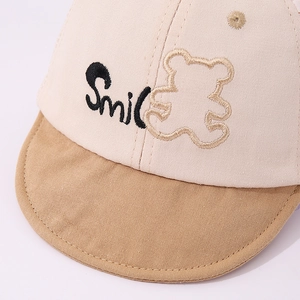 Detail der Baby-Baseballkappe mit Smile-Stickerei und Bären-Patch auf Baumwollstoff