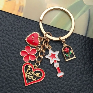 Detail of a golden keychain with red heart, rose glass dome, and star wand charms