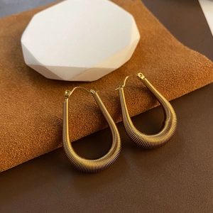 Elegant gold U-shaped hoop earrings with fine threaded texture on a minimalist stone base