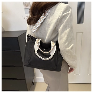 Detail view of stylish black nylon tote bag with colorful geometric wide shoulder strap