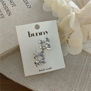 Detail view of 4-pack silver bow hair clips on premium display card with texture