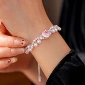 Close-up of double-row pearl bracelet with a pink gemstone center worn on a wrist