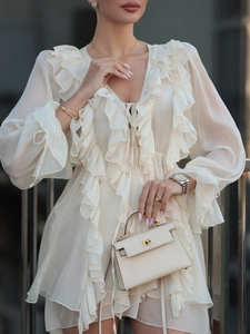 Detailed view of chiffon dress with ruffled sleeves and textured leather handbag