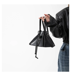 Close-up of stylish black triangular PU leather handbag with drawstring closure detail