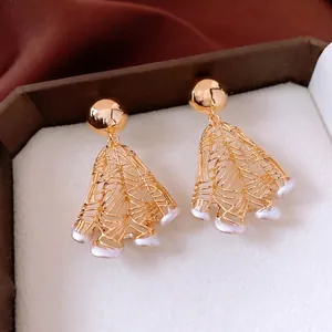 18K gold plated pearl hoop earrings with hollow leaf design on red velvet display