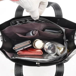 Black pebbled leather tote bag with spacious interior showing compartments and items