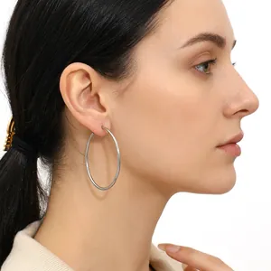 Silver hoop earrings with 5cm diameter shown worn by a model in a side profile view
