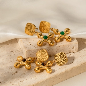 Macro shot of gold stainless steel cross earrings with tiger eye stone and hammered texture