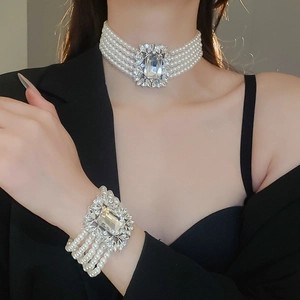 Close-up of a multilayer pearl necklace and bracelet set with large square zircon details