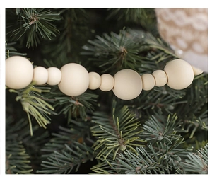 Close-up of cream wooden bead garland hanging on green pine Christmas tree branches