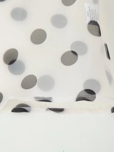 Detail of sheer white organza fabric with black polka dots and fine hem stitching