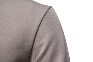Close-up detail of smooth taupe fabric texture and shoulder seam on casual sweatshirt