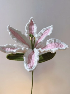 Detailed view of hand-crocheted pink lily flower with green leaves on white background