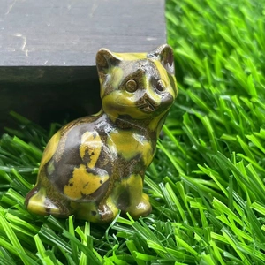 Close-up of a 1.2-inch natural stone cat figurine on grass with a polished finish