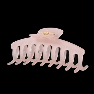 Détail d'une pince à cheveux rose pâle mat montrant sa texture givrée et son ressort doré