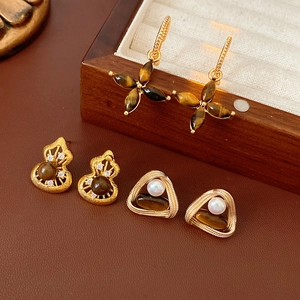 Macro detail of vintage earrings featuring tiger eye stones, pearls and gold finish