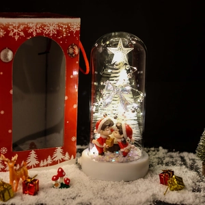 Illuminated glass dome with white Christmas tree and couple dolls with a gift box