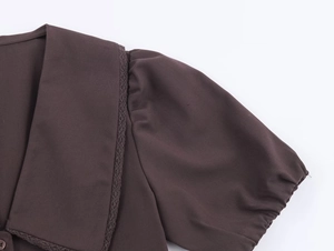 Detail of coffee puff sleeve top with lace collar and delicate woven fabric texture
