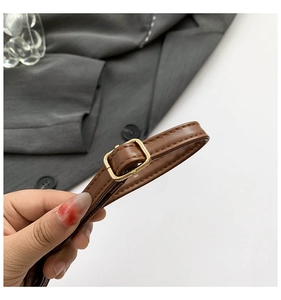 Detail of adjustable brown leather shoulder strap with a square golden metal buckle
