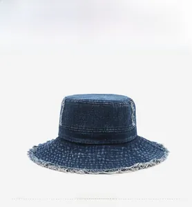 Front view detail of a dark blue washed denim bucket hat with stylish frayed edges