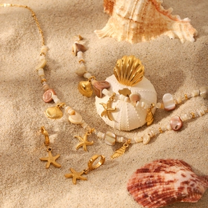 Golden starfish and shell jewelry set with natural stones on a sunny beach sand background