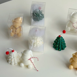 Detailed view of hand-painted mini Christmas tree and bear scented candles in gift boxes