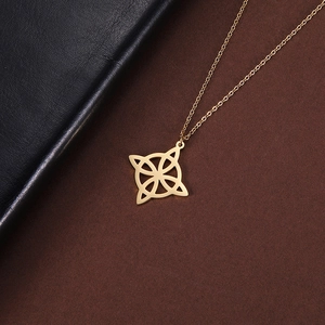Detailed view of a gold clover pendant necklace on textured brown paper background