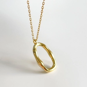 Minimalist gold irregular oval pendant necklace with a polished liquid metal aesthetic