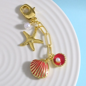 Portachiavi di lusso con stella marina dorata e conchiglia in smalto rosso su ceramica