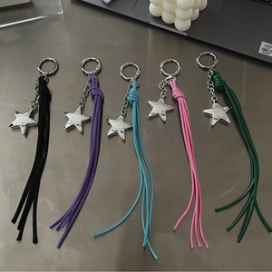Star-shaped tassel pendants in five colors arranged on a metallic surface for bags