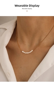 Close-up of elegant gold chain necklace with nine white freshwater pearls on a model
